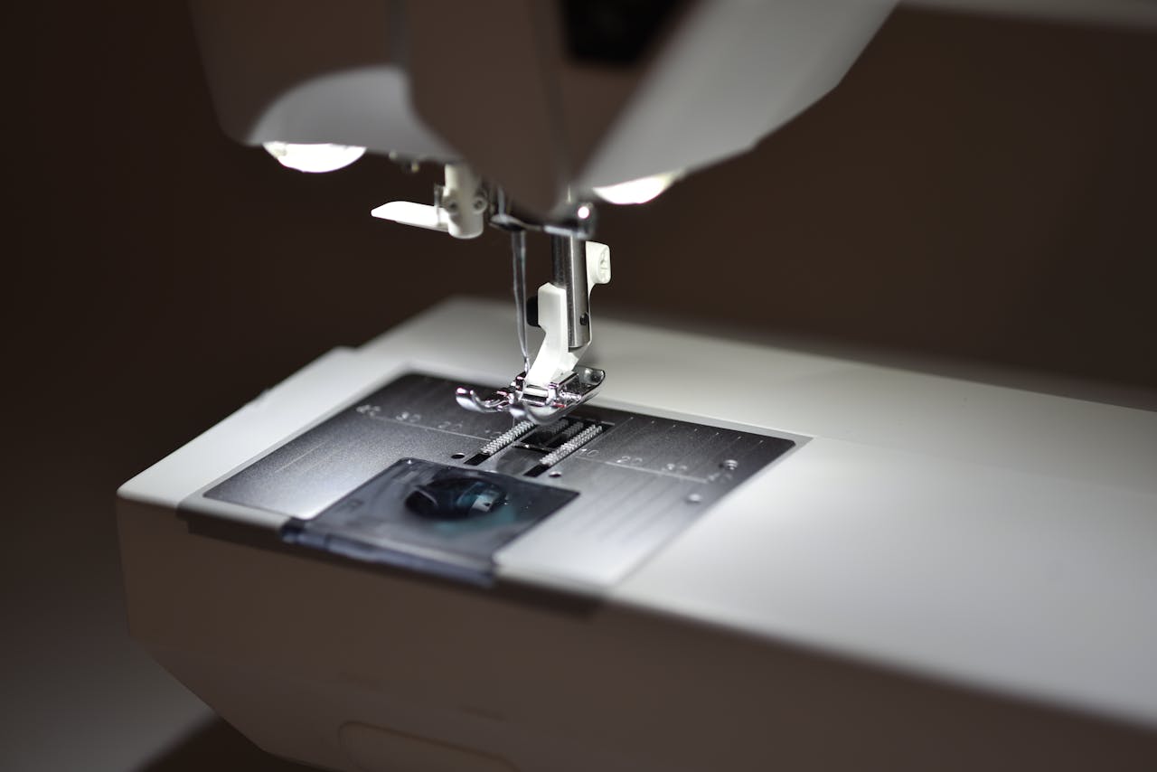 Detailed view of a sewing machine's presser foot illuminated by soft lighting.
