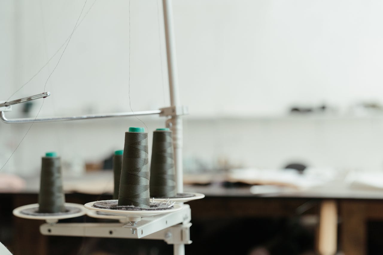 Detailed view of thread spools in a sewing workspace, highlighting precision craft tools.